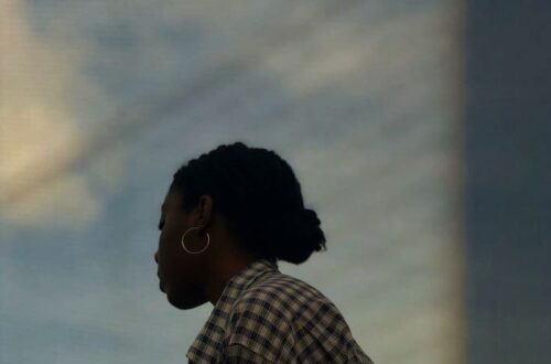Pensive woman under a soft sky, caught in a moment of emotional clarity.