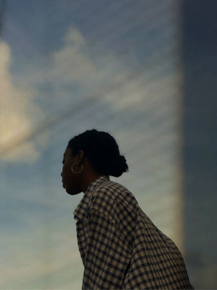 Pensive woman under a soft sky, caught in a moment of emotional clarity.