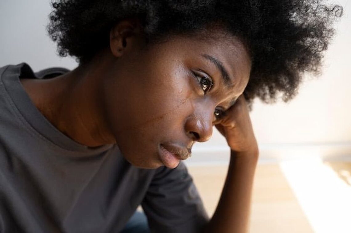 Close-up of a young African woman with tears on her face, looking thoughtful and sad.