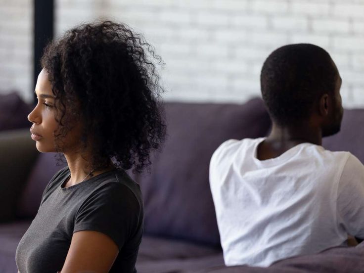 A Black couple backing each other. The lady is wearing a sad look, while the male's face is blurred in the background.