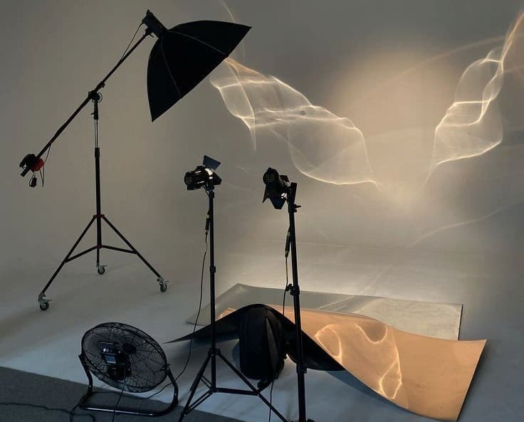 A cluttered photography studio with equipments, and light beams cutting through