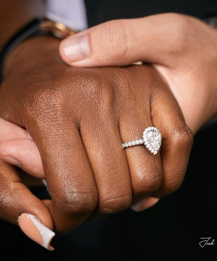 An up-close photo of a female hand wearing a ring. The female hand is holding a man's hand under hers.